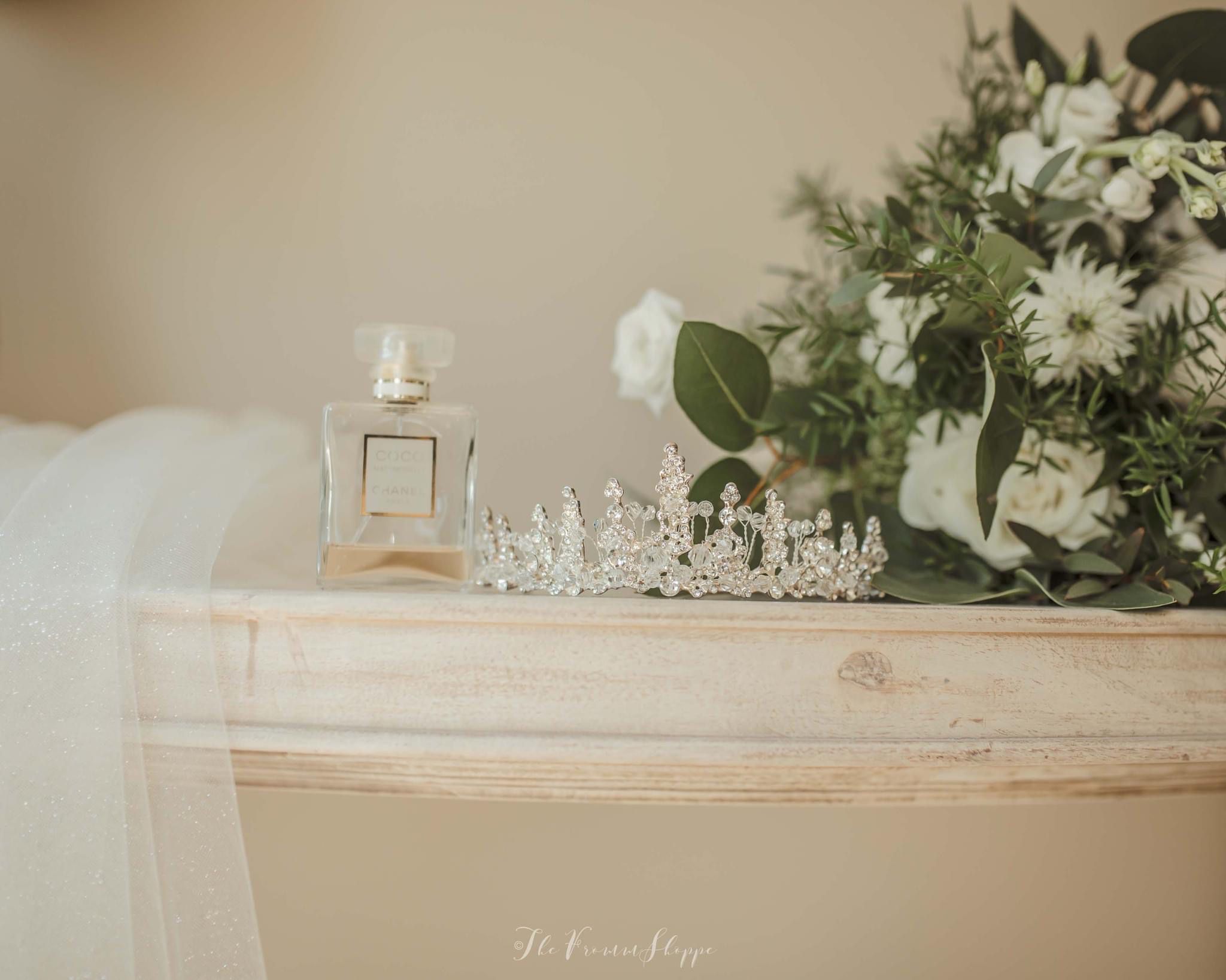 Photographe of diamond tiara on a dressing table with white flowers and perfume. Credit The Fromme Shoppe.